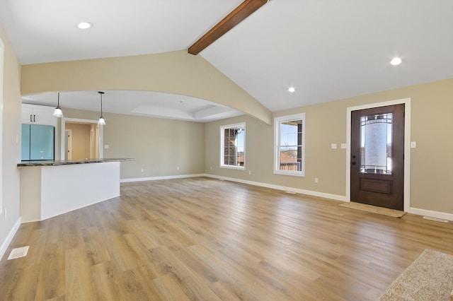 unfurnished living room with light wood-type flooring, vaulted ceiling with beams, visible vents, and baseboards