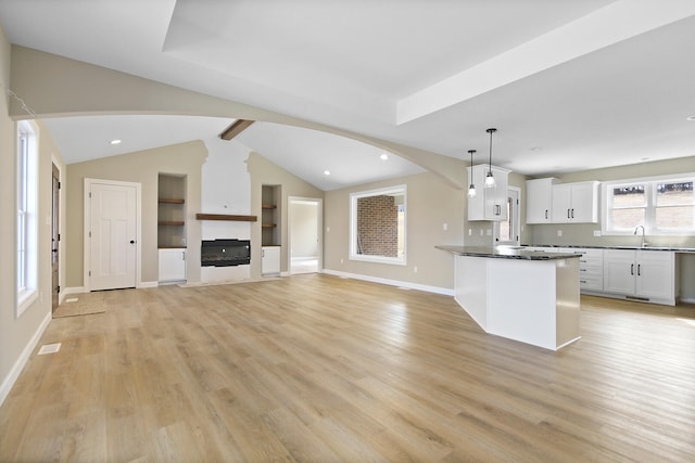 kitchen featuring light wood-style floors, dark countertops, white cabinets, and vaulted ceiling with beams