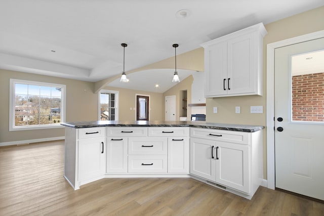 kitchen with light wood finished floors, visible vents, a peninsula, hanging light fixtures, and white cabinetry