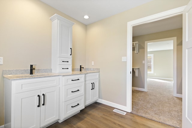 bathroom featuring baseboards, visible vents, a sink, and wood finished floors