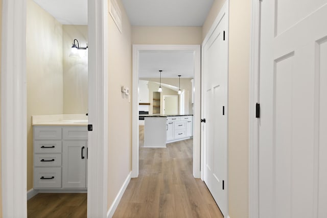 corridor featuring light wood-style flooring and baseboards