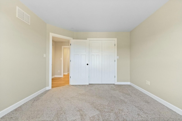 unfurnished bedroom featuring baseboards, a closet, visible vents, and carpet flooring