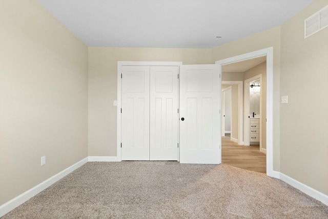 unfurnished bedroom with carpet floors, a closet, visible vents, and baseboards