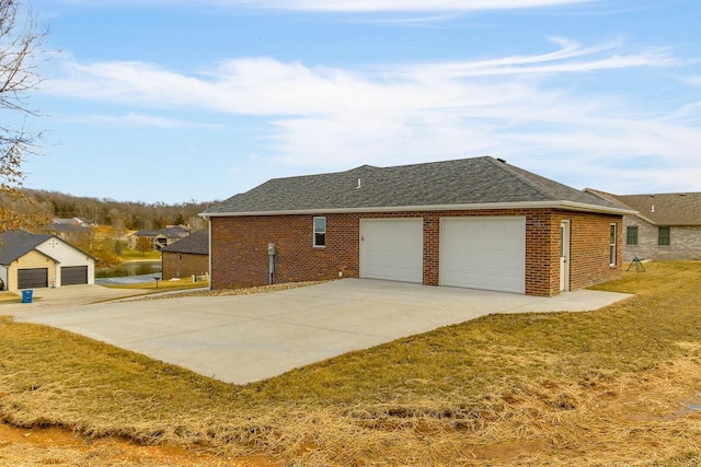 view of home's exterior with brick siding, roof with shingles, concrete driveway, a lawn, and an attached garage