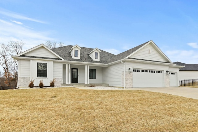 view of front facade with covered porch, an attached garage, stone siding, driveway, and a front lawn