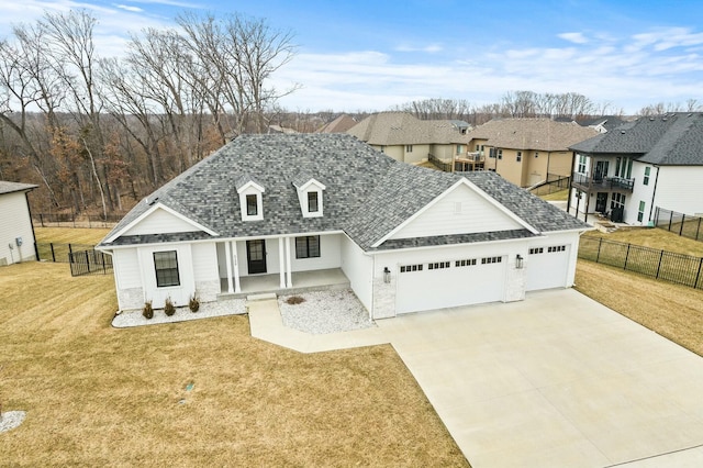 view of front facade featuring a shingled roof, concrete driveway, an attached garage, a front yard, and fence