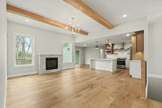 unfurnished living room with light wood-type flooring, a notable chandelier, baseboards, and beamed ceiling