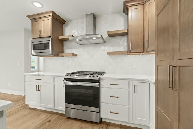 kitchen featuring open shelves, wall chimney range hood, light wood-type flooring, and appliances with stainless steel finishes