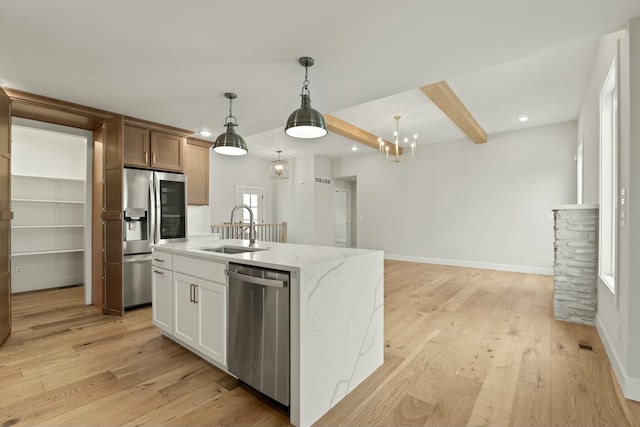 kitchen featuring light wood-type flooring, light stone countertops, stainless steel appliances, and a sink