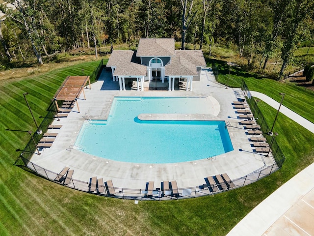 pool with a patio area, fence, and a yard