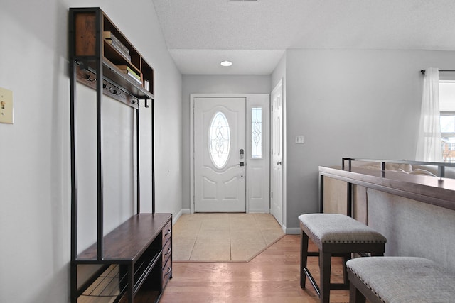 entryway with baseboards, a textured ceiling, and light wood finished floors