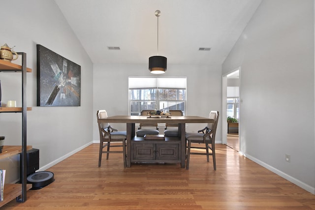 dining space featuring lofted ceiling, baseboards, visible vents, and wood finished floors