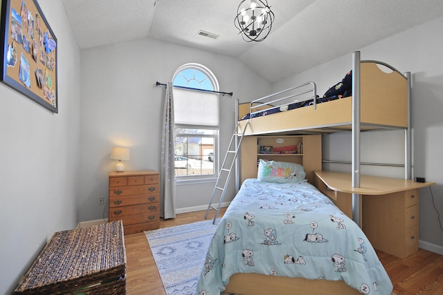 bedroom with baseboards, visible vents, wood finished floors, vaulted ceiling, and a textured ceiling