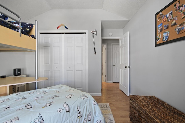 bedroom featuring a textured ceiling, vaulted ceiling, a closet, and wood finished floors