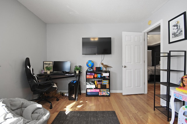 home office with a textured ceiling, baseboards, and wood finished floors