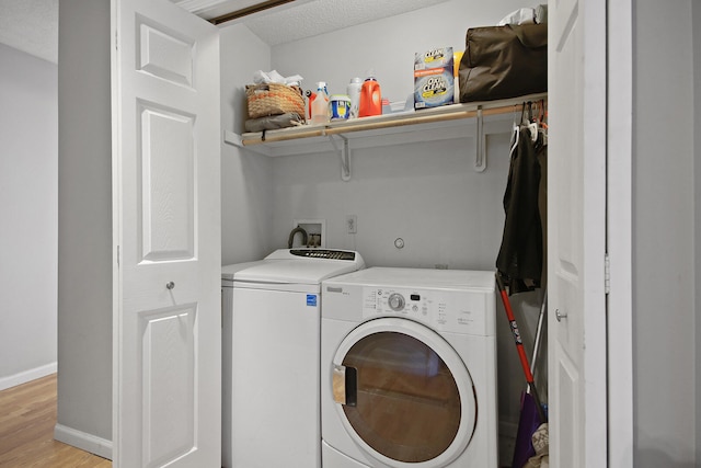 washroom featuring laundry area, light wood finished floors, baseboards, a textured ceiling, and washing machine and dryer