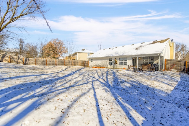 snow covered rear of property with a fenced backyard