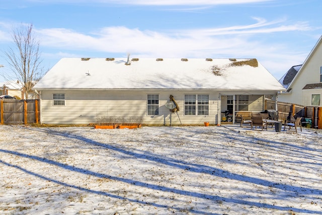 snow covered rear of property featuring a patio area and fence