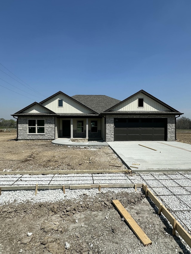 view of front facade with driveway, stone siding, and an attached garage