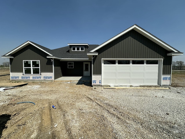 view of front facade featuring dirt driveway, an attached garage, and roof with shingles