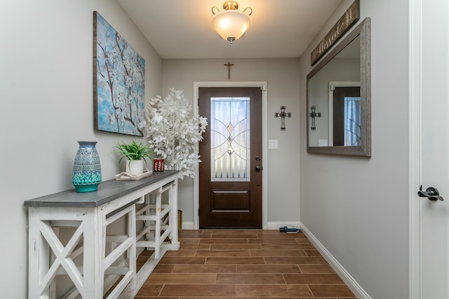 doorway to outside featuring baseboards and wood finish floors