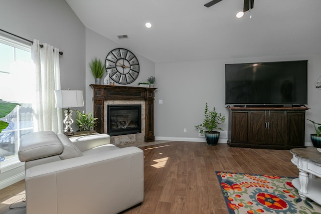 living room featuring lofted ceiling, a fireplace, wood finished floors, visible vents, and baseboards