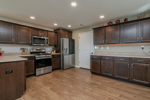 kitchen with light wood finished floors, light countertops, appliances with stainless steel finishes, and dark brown cabinetry