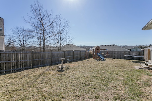 view of yard with a fenced backyard, a trampoline, and a playground