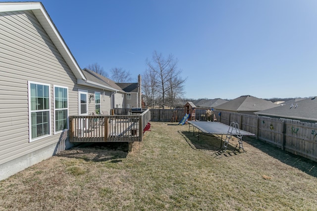 view of yard featuring a trampoline, a playground, a fenced backyard, and a wooden deck