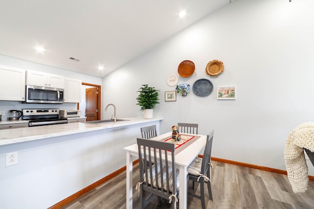 dining room featuring lofted ceiling, visible vents, baseboards, and wood finished floors