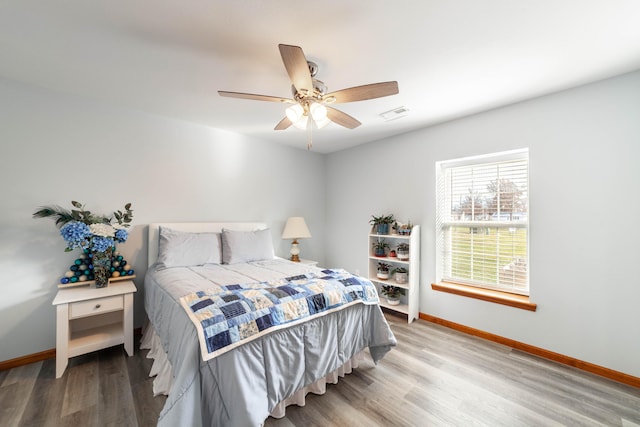 bedroom featuring visible vents, ceiling fan, baseboards, and wood finished floors