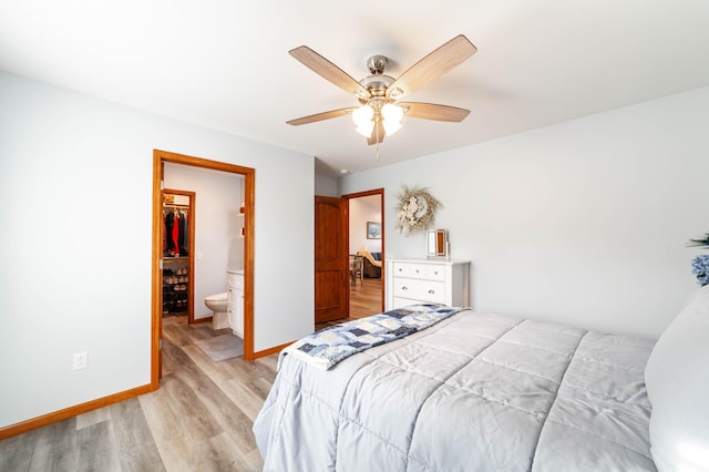 bedroom featuring light wood finished floors, a closet, a spacious closet, ceiling fan, and baseboards