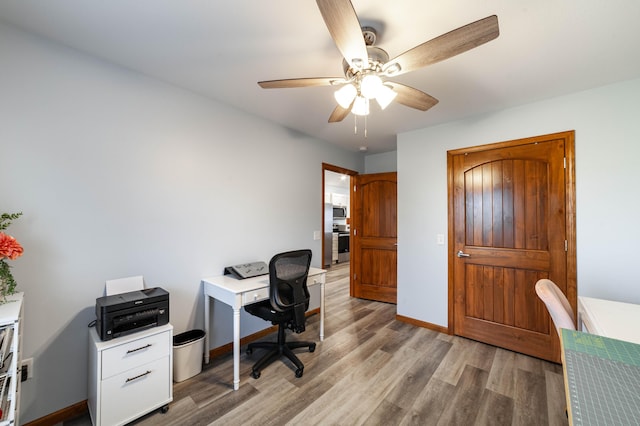 office with light wood-style flooring, baseboards, and a ceiling fan