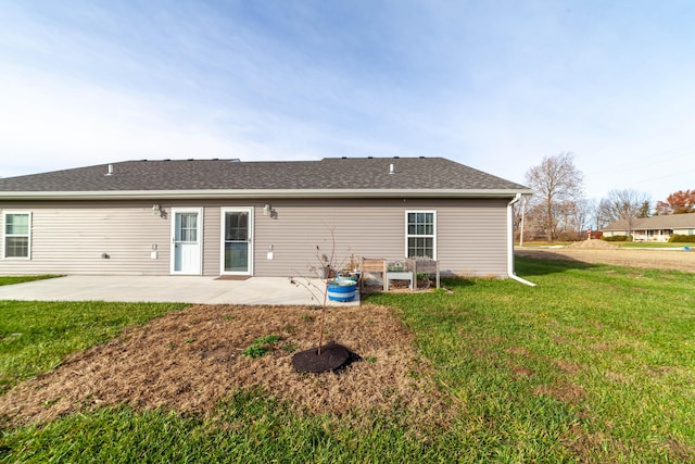 rear view of house featuring a yard, roof with shingles, and a patio area