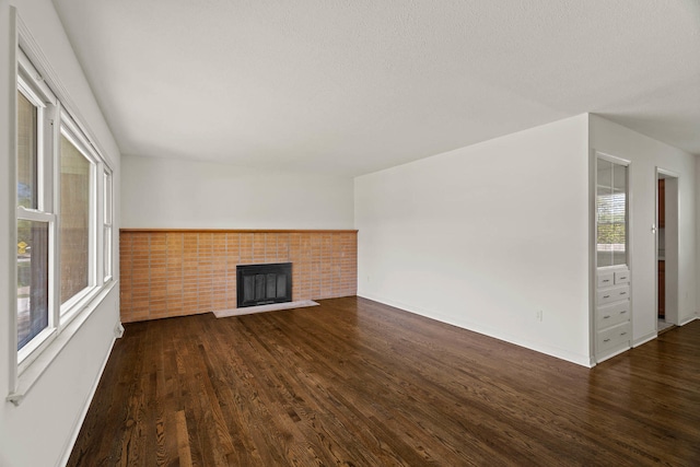 unfurnished living room with a fireplace with raised hearth and dark wood finished floors