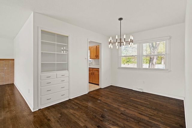 unfurnished dining area featuring dark wood-style floors, a chandelier, visible vents, and baseboards