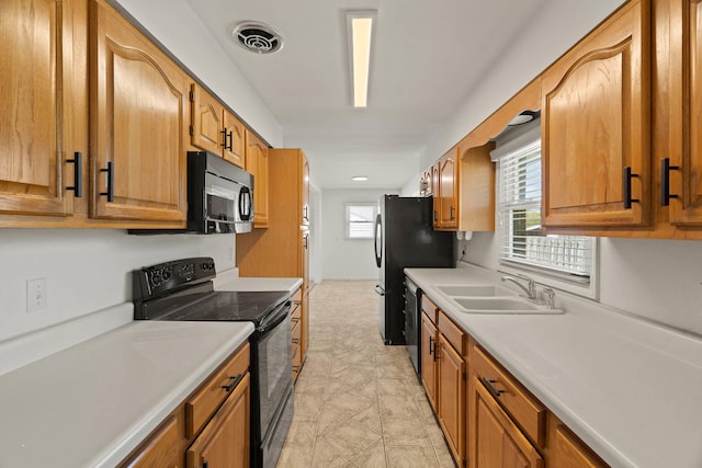 kitchen with light countertops, a sink, visible vents, and black appliances