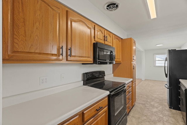 kitchen with brown cabinets, light countertops, visible vents, and black appliances