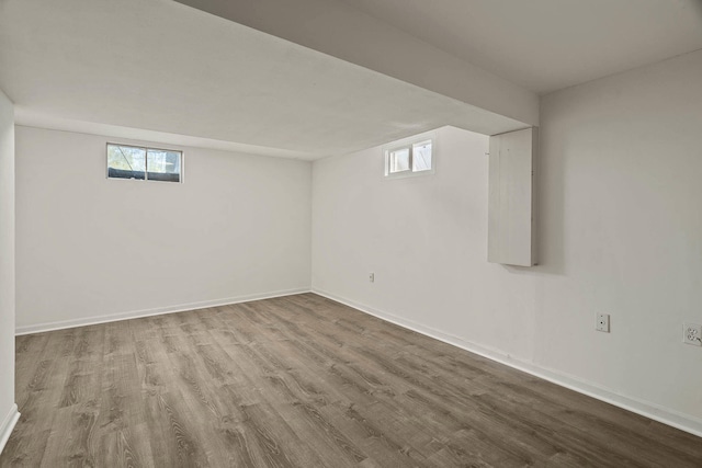 basement featuring a healthy amount of sunlight, baseboards, and wood finished floors