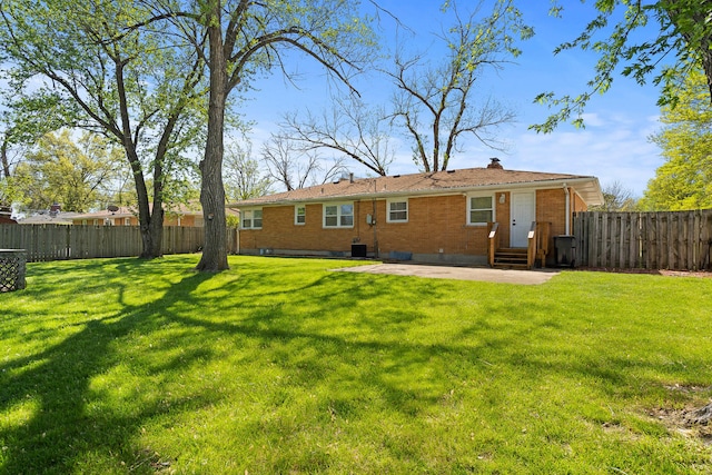 rear view of property with a yard, a fenced backyard, and brick siding