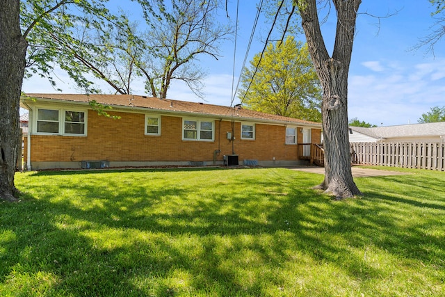 back of house featuring a yard, brick siding, central AC, and fence