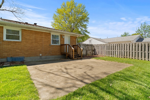 back of property featuring a patio area, fence, a lawn, and brick siding