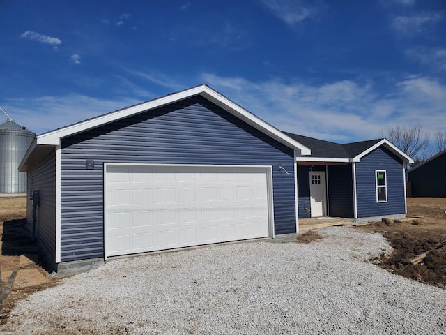 ranch-style home with a garage and gravel driveway