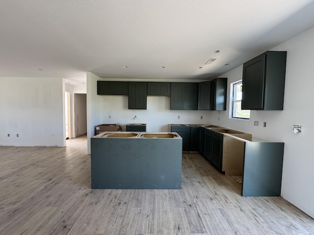 kitchen with a kitchen island, light wood finished floors, and visible vents