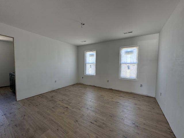 unfurnished room with wood finished floors and visible vents