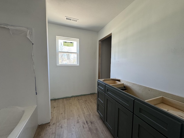 full bath with wood finished floors, visible vents, and a bathing tub