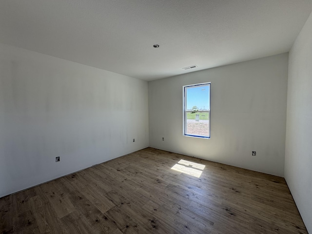 empty room with wood finished floors and visible vents