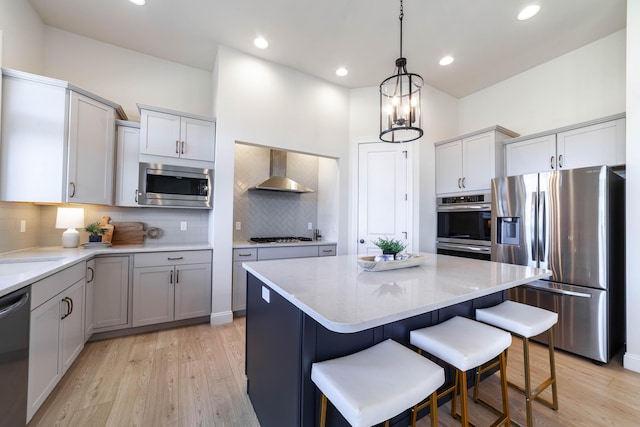 kitchen featuring tasteful backsplash, a kitchen island, a breakfast bar area, stainless steel appliances, and wall chimney range hood