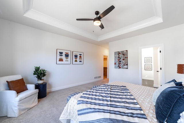 carpeted bedroom featuring a tray ceiling, visible vents, ornamental molding, connected bathroom, and baseboards