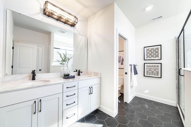 bathroom with visible vents, a sink, toilet, and double vanity